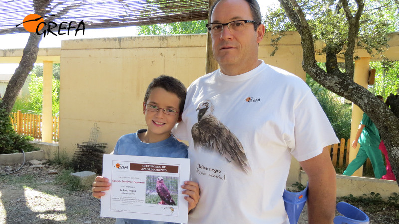 El niño Gonzalo Gutiérrez exhibe junto a su padre el certificado de haber apadrinado un milano negro. Foto GREFA