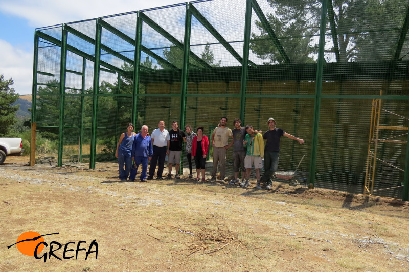 Foto de grupo con trabajadores y voluntarios de GREFA delante del jaulón de aclimatación construido para los buitres negros en La Demanda burgalesa.