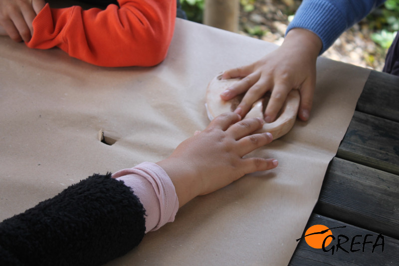 Unos niños juegan con réplicas de huellas de animales en uno de nuestros talleres.