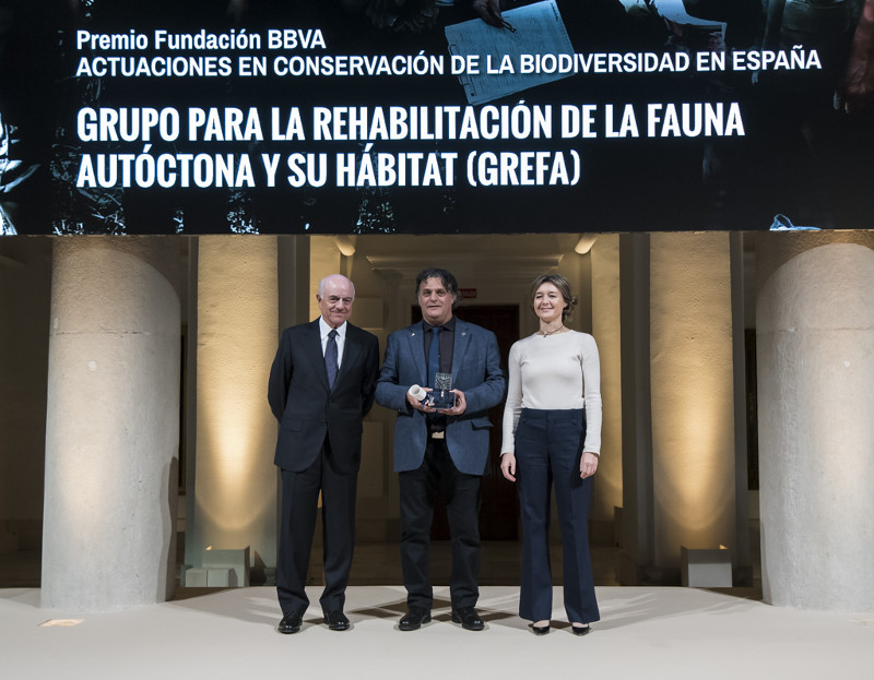 Ernesto Álvarez, presidente de GREFA, muestra el premio, flanqueado por el presidente de la Fundación BBVA y la ministra de Medio Ambiente.