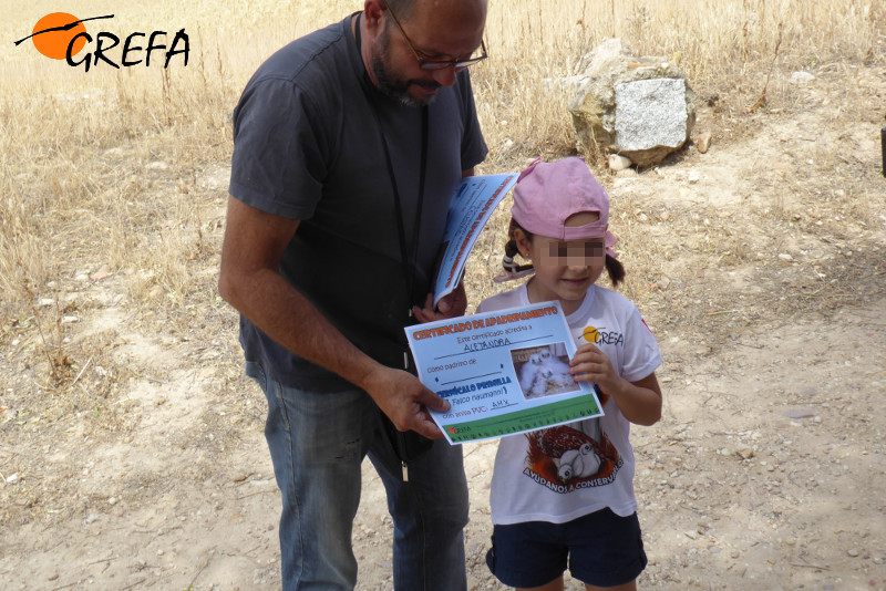 Una niña recibe el diploma que le acredita como madrina de un pollo de cernícalo primilla.