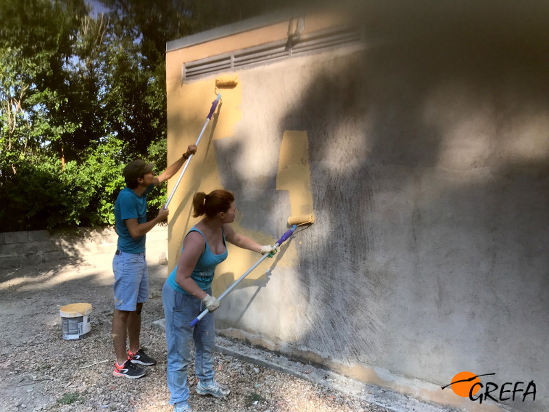 Dos voluntarios internacionales pintan las paredes del futuro centro de interpretación.