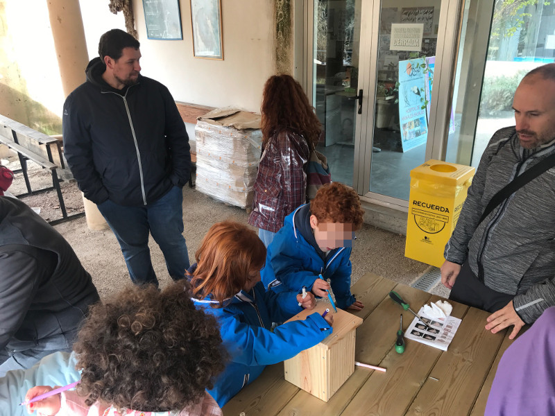 Unos niños y sus familias participan en el taller de cajas nido que propusimos a los vecinos de Alcalá de Henares que nos visitaron.