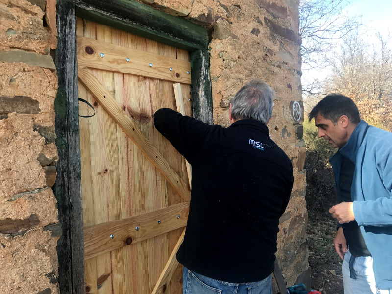Dos maragatos ilustres colocan la puerta de la caseta rehabilitada: Luis Gonzalo y Bernando Alonso.