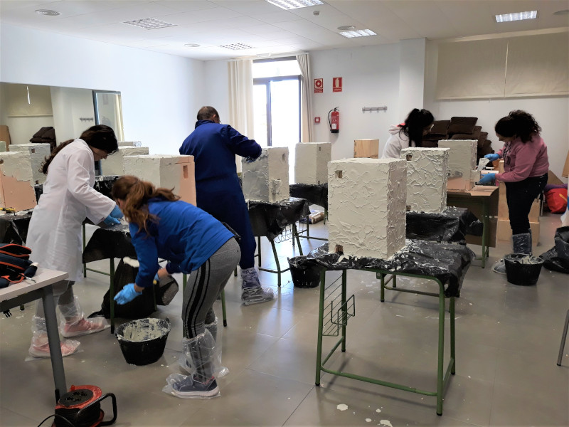 Los asistentes al taller aplicando la capa de mortero a las cajas nido.