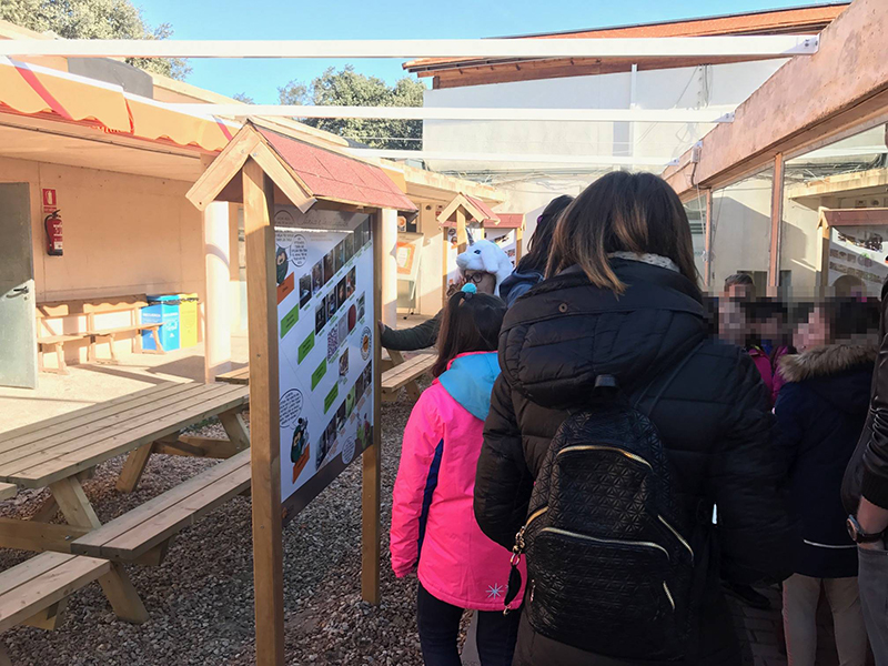 Varios niños y sus profesores junto a uno de los carteles del área de educación ambiental aledaña al hospital de fauna de GREFA.