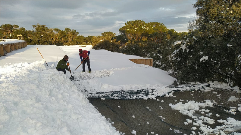 Dos trabajadores de GREFA quitan la nieve acumulada en una azotea de nuestro hospital de fauna salvaje.