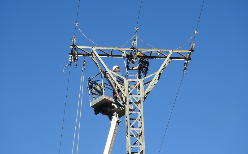 Dos operarios corrigen el apoyo de un tendido eléctrico en el entorno de la zona cantábrica de liberación de los pigargos europeos.