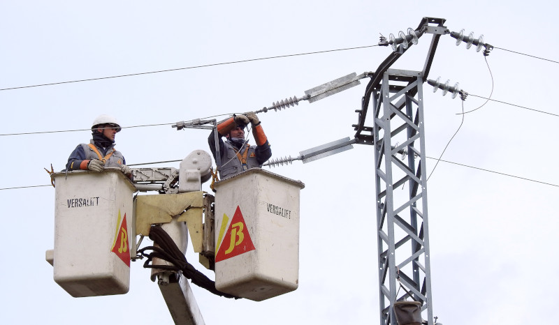 Dos operarios instalan medidas anti-electrocución de aves en un tendido eléctrico.