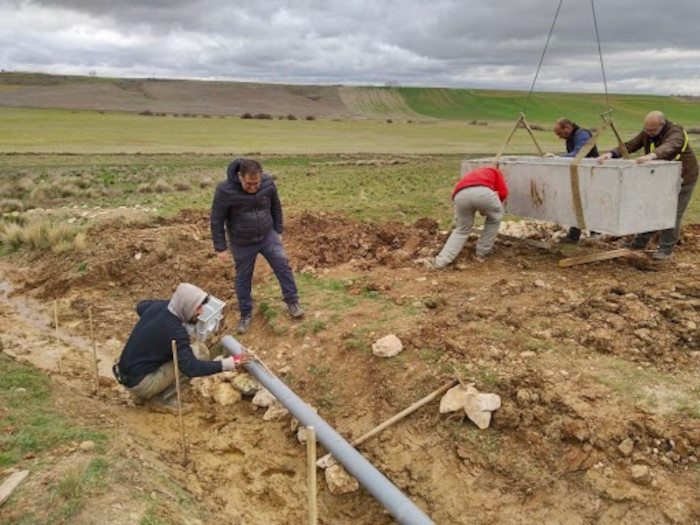 Trabajadores y voluntarios de GREFA nivelan la conducción de agua y descargan uno de los abrevaderos.