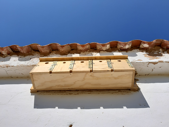 "Gorrionera" de diseño horizontal con cinco nidos instalada en la pared de una construcción rural.